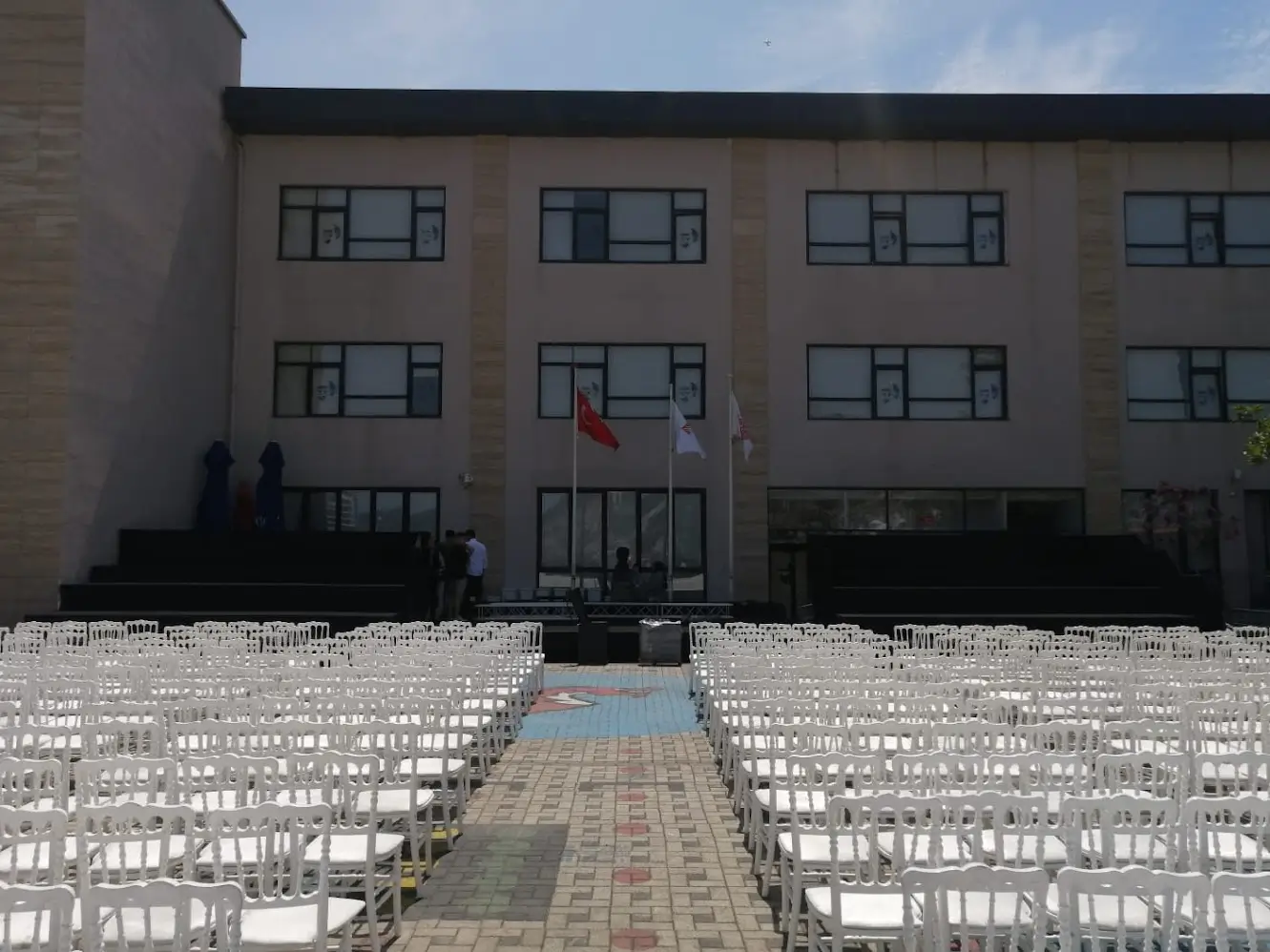 Outdoor theatre-style seating with white chairs facing an event stage