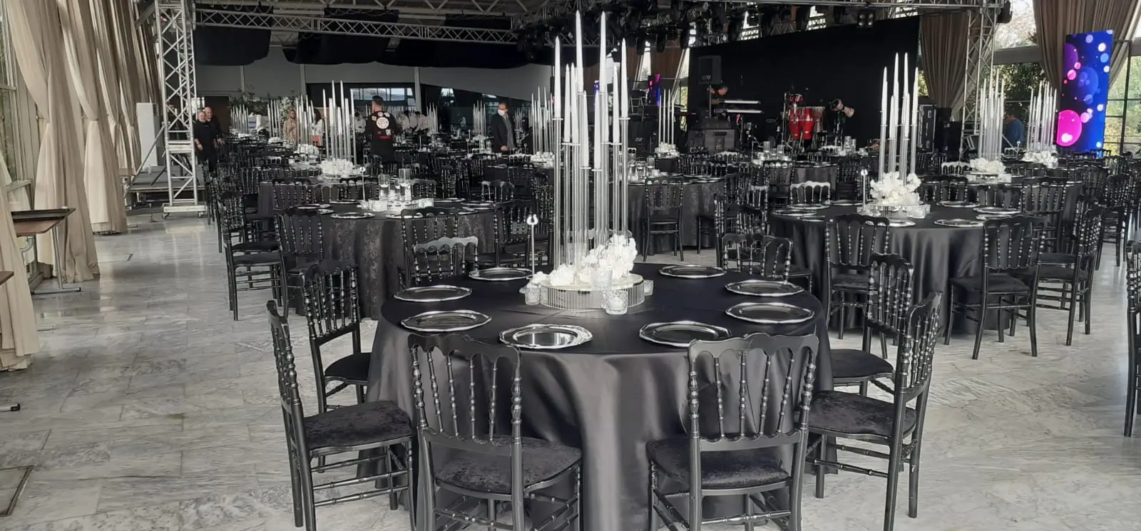 Round banquet tables with black chairs facing a live event stage